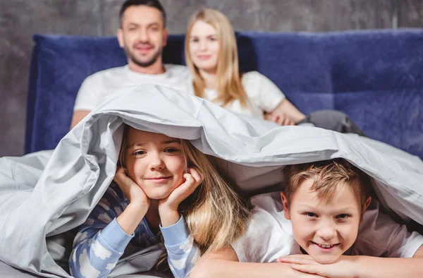 Glückliche Geschwister unter Bettdecke — Stockfoto