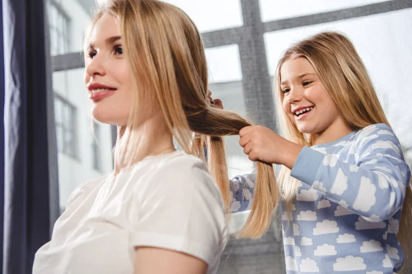 Daughter plaiting braid of mother — Stock Photo