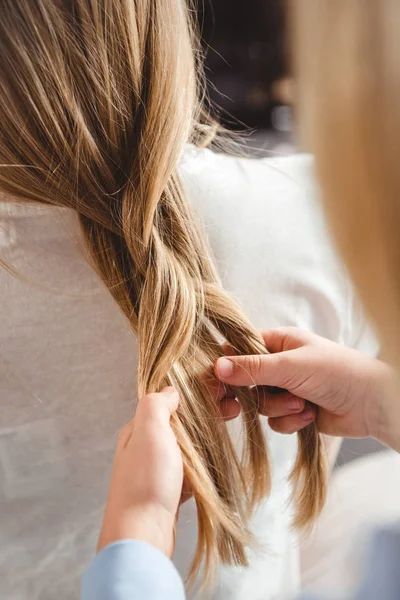 Daughter plaiting braid of mother — Stock Photo