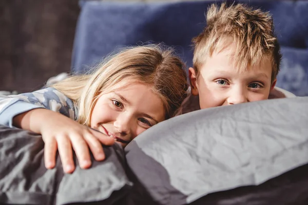 Fratello e sorella sdraiati su cuscini — Foto stock