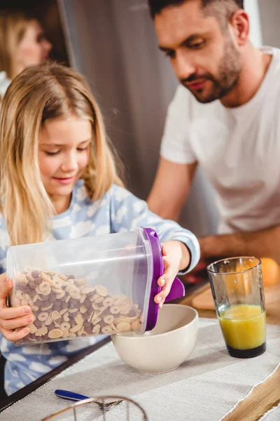 Mädchen gießt Kornflockenringe — Stockfoto