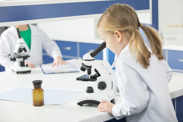 Schoolgirl using microscope — Stock Photo