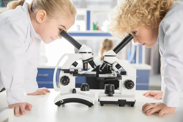 Schoolchildren using microscopes — Stock Photo