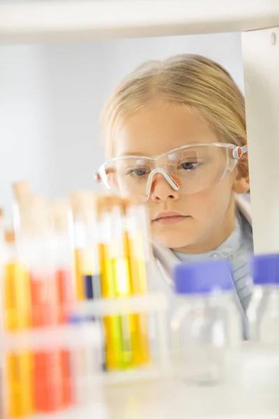 Schoolgirl looking at test tubes — Stock Photo