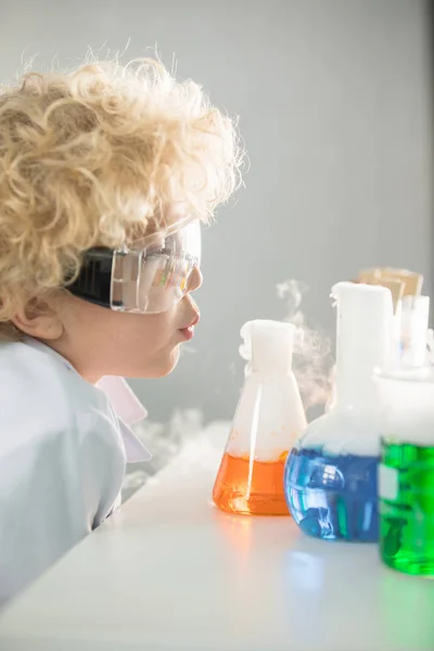 Schoolboy looking at flasks — Stock Photo