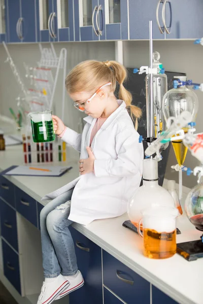 Schoolgirl holding flask with sample — Stock Photo