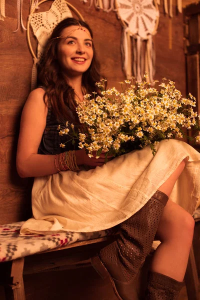 Bohemian woman sitting with bouquet of chamomiles — Stock Photo