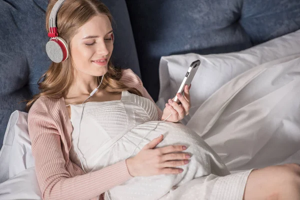 Femme enceinte avec écouteurs — Photo de stock