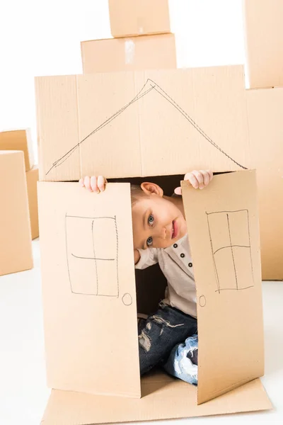 Niño sentado dentro de la caja de cartón - foto de stock