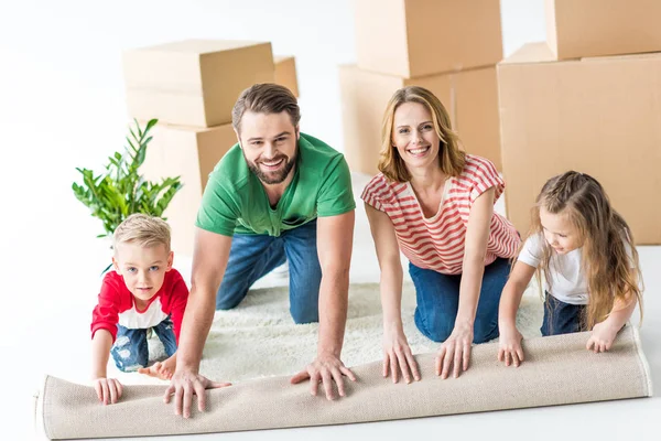 Family unrolling carpet — Stock Photo