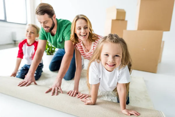 Family unrolling carpet — Stock Photo