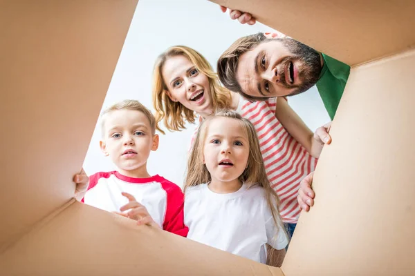 Família espreitando da caixa de papelão — Fotografia de Stock