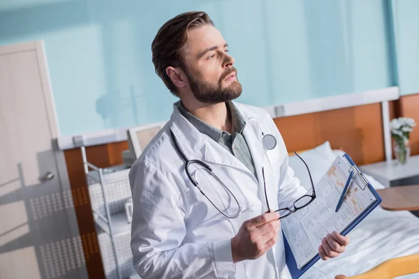 Médico masculino segurando óculos — Fotografia de Stock