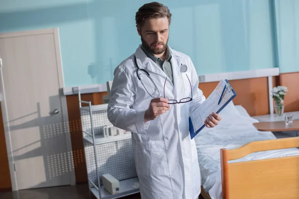 Médico masculino segurando óculos — Fotografia de Stock