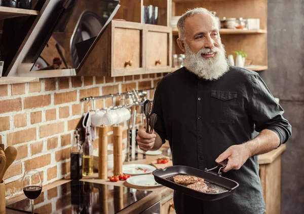 Homem cozinhando bifes — Fotografia de Stock