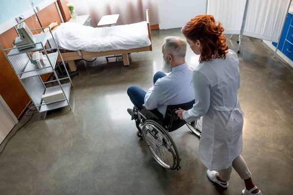 Médico y paciente en silla de ruedas - foto de stock