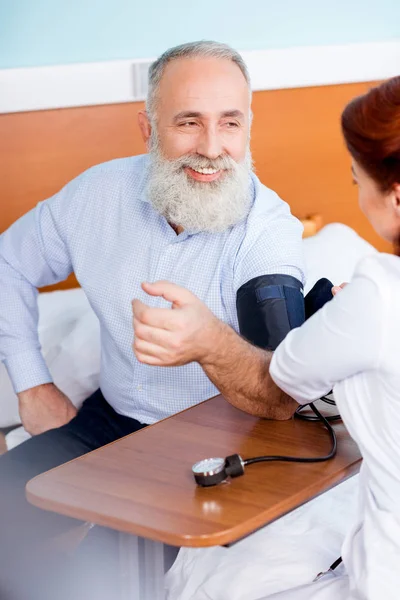 Médico que mide la presión del paciente - foto de stock