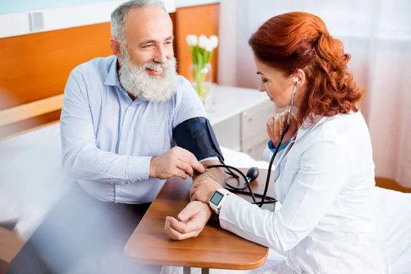 Médico que mide la presión del paciente - foto de stock