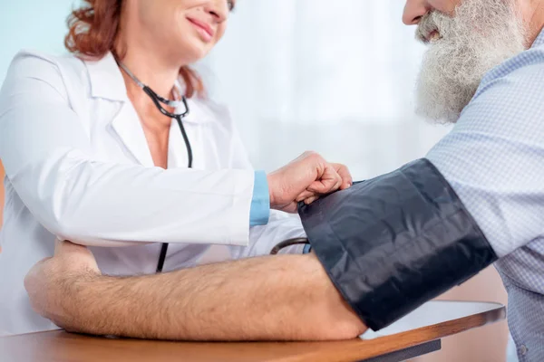 Médico que mide la presión del paciente - foto de stock