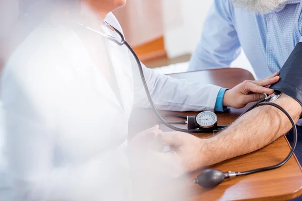 Doctor measuring pressure of patient — Stock Photo