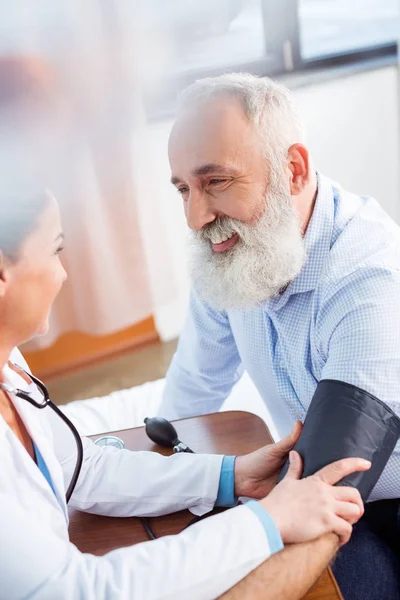 Médico que mide la presión del paciente - foto de stock