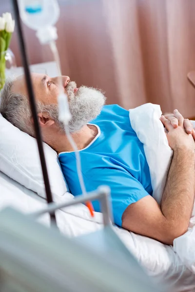 Hombre mayor en cama de hospital - foto de stock