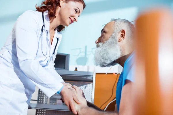 Doctor holding hands of patient — Stock Photo
