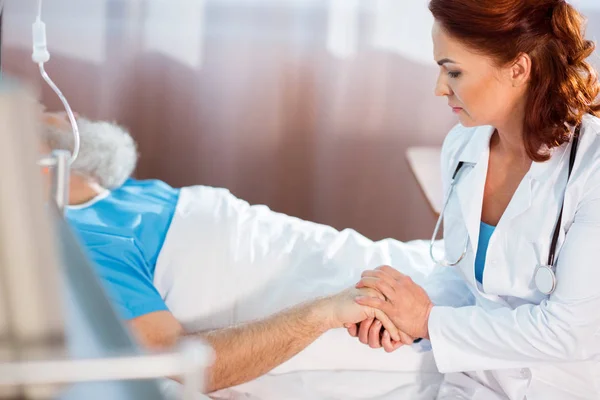 Doctor holding hand of patient — Stock Photo
