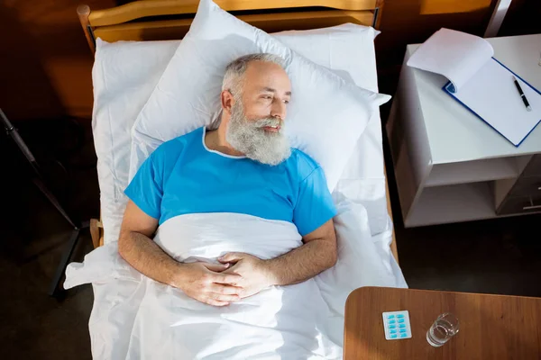 Hombre mayor en cama de hospital - foto de stock