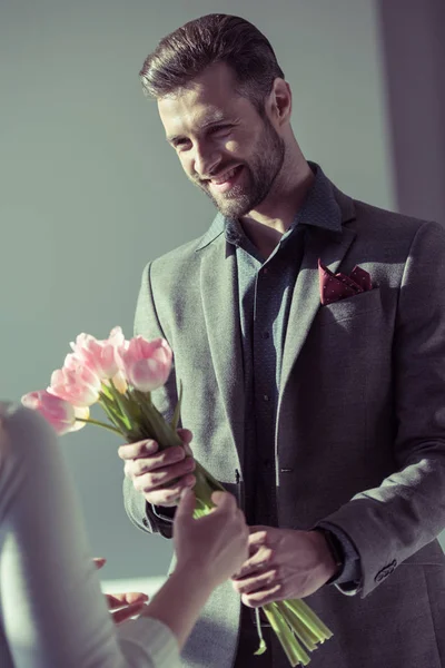Hombre presentando flores a la mujer - foto de stock