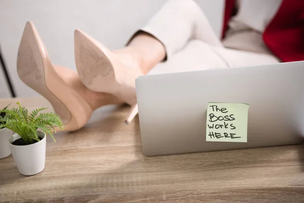 Jambes féminines près d'un ordinateur portable — Photo de stock