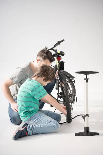 Padre e hijo inflando neumático de bicicleta - foto de stock