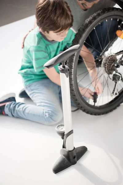 Padre e hijo inflando neumático de bicicleta - foto de stock