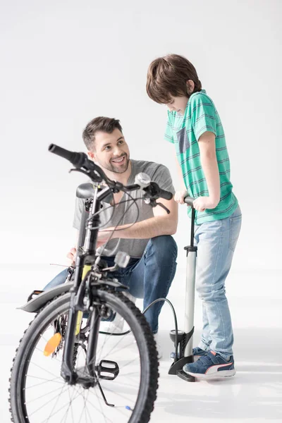 Padre e hijo inflando neumático de bicicleta - foto de stock