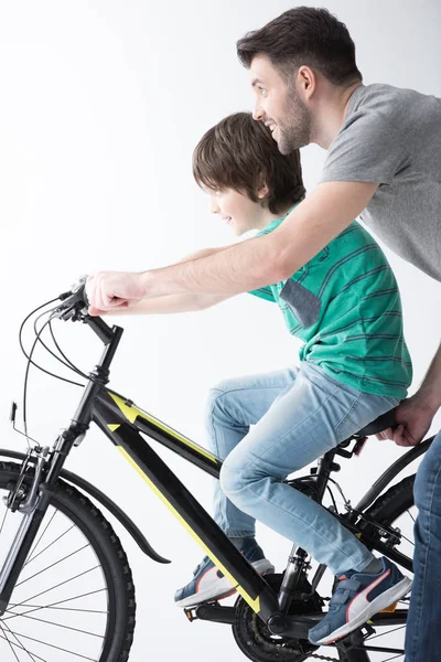 Padre ayudando a su hijo a montar en bicicleta - foto de stock