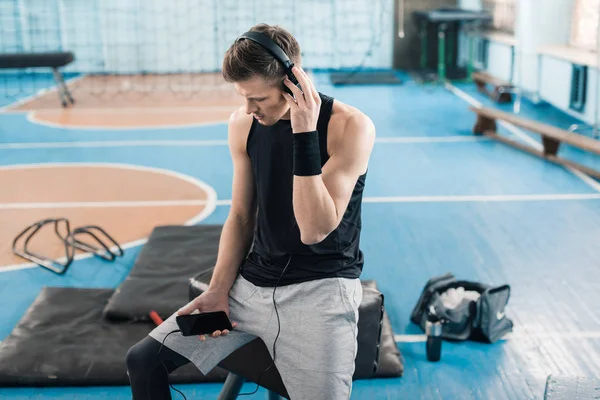 Sportsman dans les écouteurs avec smartphone — Photo de stock