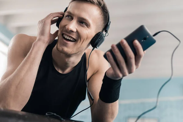 Sportsman in headphones with smartphone — Stock Photo