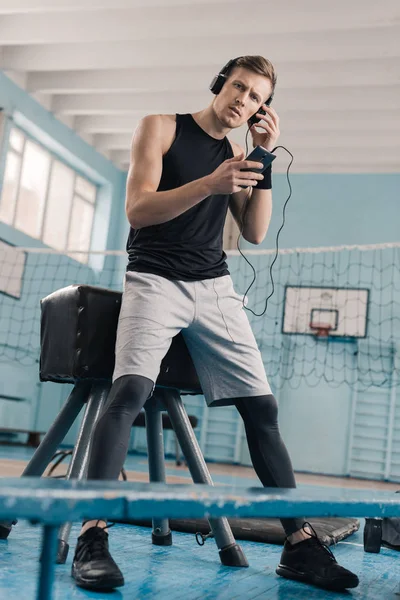 Sportsman dans les écouteurs avec smartphone — Photo de stock