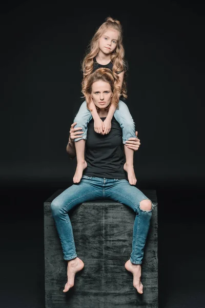 Daughter sitting on mother's shoulders — Stock Photo