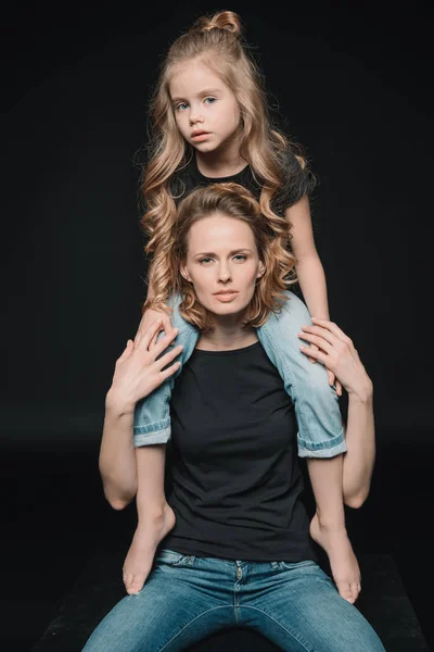 Daughter sitting on mother's shoulders — Stock Photo