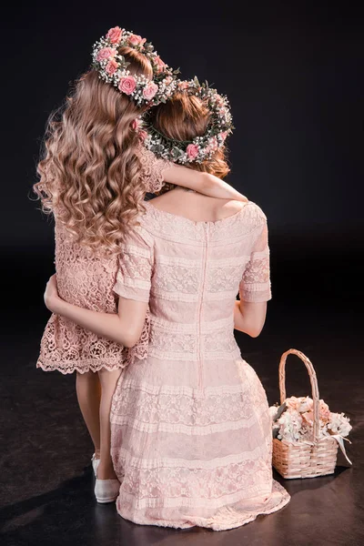 Madre e hija en flores guirnaldas - foto de stock