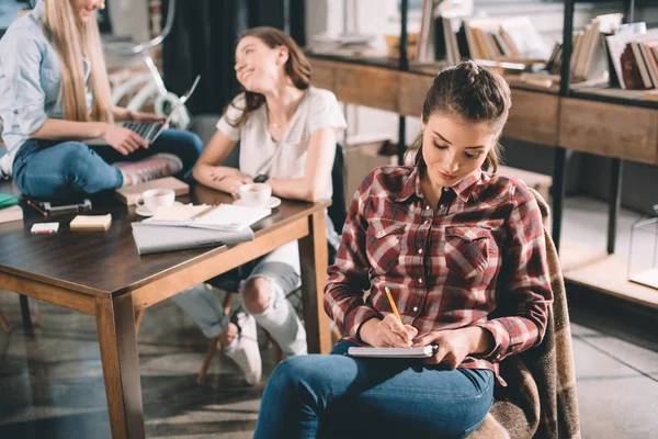 Frau studiert und schreibt in Textbuch — Stockfoto