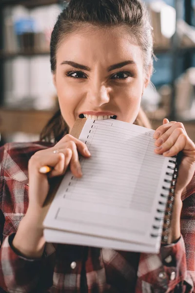 Chica mordiendo copybook - foto de stock