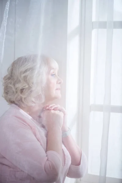 Mujer mayor en la ventana - foto de stock