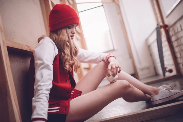 Mujer hipster con estilo en chaqueta de béisbol sentado con pelota de béisbol - foto de stock