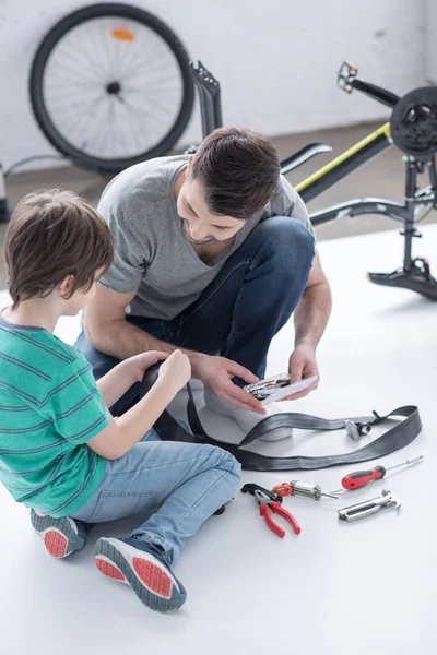 Pai e filho reparando pneu de bicicleta — Fotografia de Stock