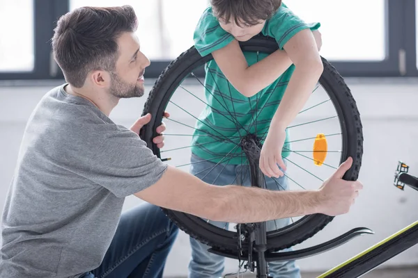 Padre e hijo reparando bicicleta - foto de stock