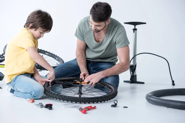 Padre e hijo reparando bicicleta - foto de stock