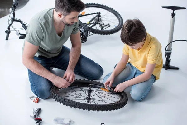 Filho e pai reparando bicicleta — Fotografia de Stock