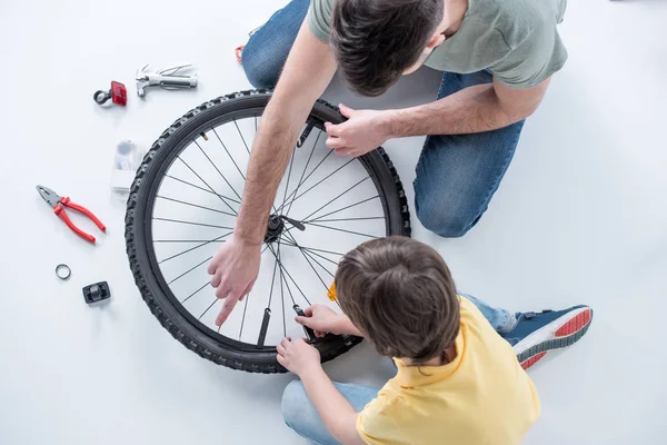 Hijo y padre reparando bicicleta - foto de stock